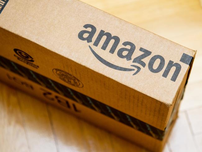 Amazon logotype printed on cardboard box side seen from above on a wooden parquet floor. Amazon is an American electronic e-commerce company distribution worlwide e-commerce goods