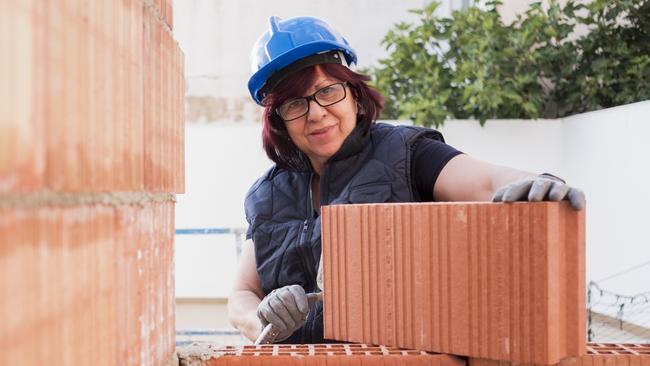 mature woman bricklayer lays bricks in the construction and remodeling of the terrace room of a house. Picture: iStock