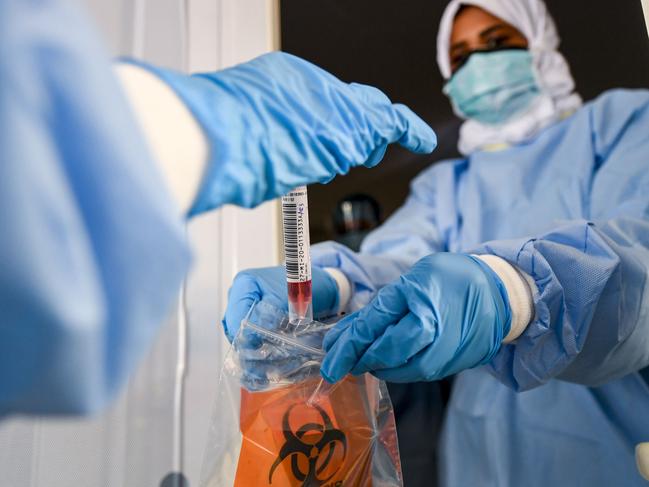 TOPSHOT - Laboratory workers bag a biological sample at a drive-through COVID-19 coronavirus testing centre in al-Khawaneej district of the gulf emirate of Dubai on April 9, 2020. (Photo by KARIM SAHIB / AFP)