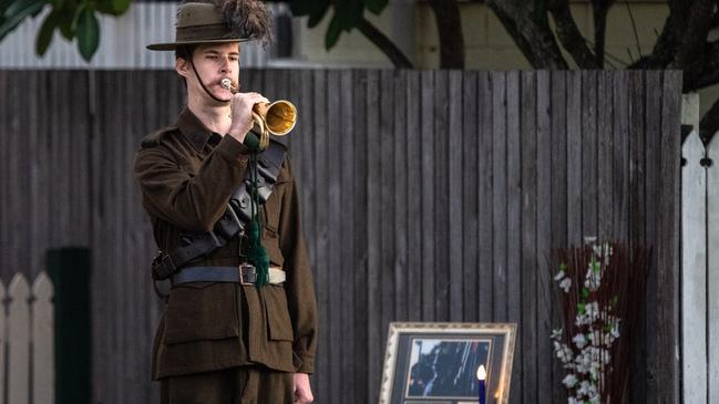 Lighting up the dawn  Anzac Day Berrima Street Wynnum The bugler is Derek Miller (whoÕs been playing for nine years), wearing a Light Horse outfit.] photo Neale Maynard