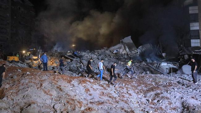 People and first responders stand on the rubble of a building destroyed in an Israeli air strike on Beirut's southern suburbs, targeting Hassan Nasrallah. Picture: AFP.