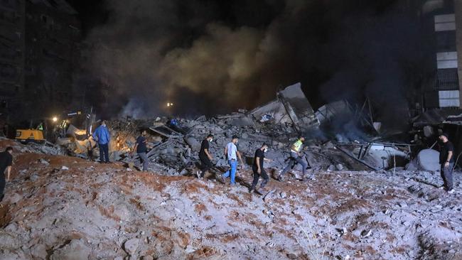 People and first responders stand on the rubble of a building destroyed in an Israeli air strike on Beirut's southern suburbs, targeting Hassan Nasrallah. Picture: AFP.