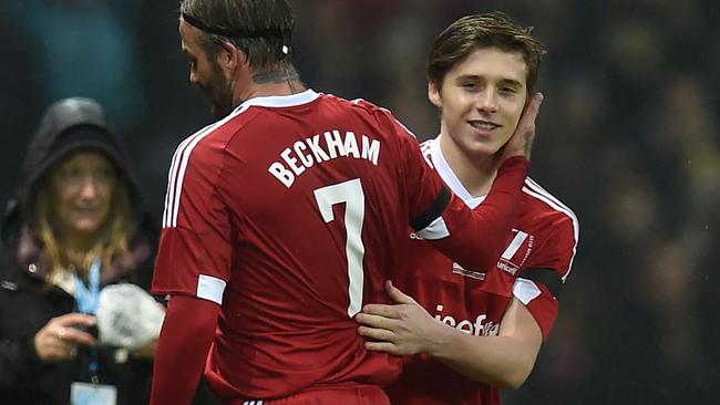 GB and Ireland's English captain David Beckham (L) is substituted for his son Brooklyn during a charity football match between a Great Britain and Ireland team and a Rest of the World team at Old Trafford in Manchester, north west England November 14, 2015 in aid of UNICEF. AFP PHOTO / PAUL ELLIS