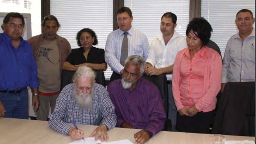 Uncle Bob Anderson and applicant Ian Delaney, right, sign the agreement in principle for a state ILUA watched by Quandamooka family representatives.