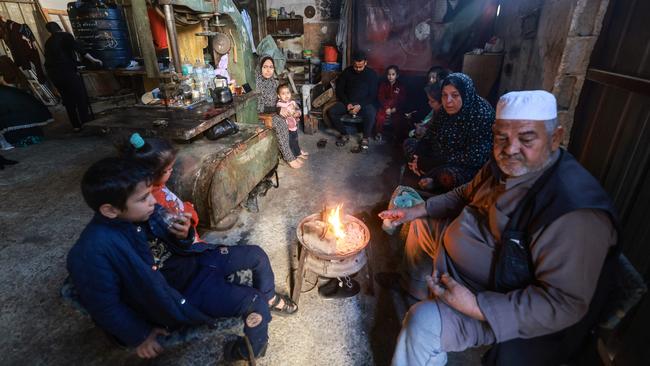 Members of a Palestinian family who fled Gaza City to Khan Yunis and had to recently flee to Rafah in the southern Gaza Strip, gather around a small fire, inside a workshop where they found temporary shelter. Picture: AFP