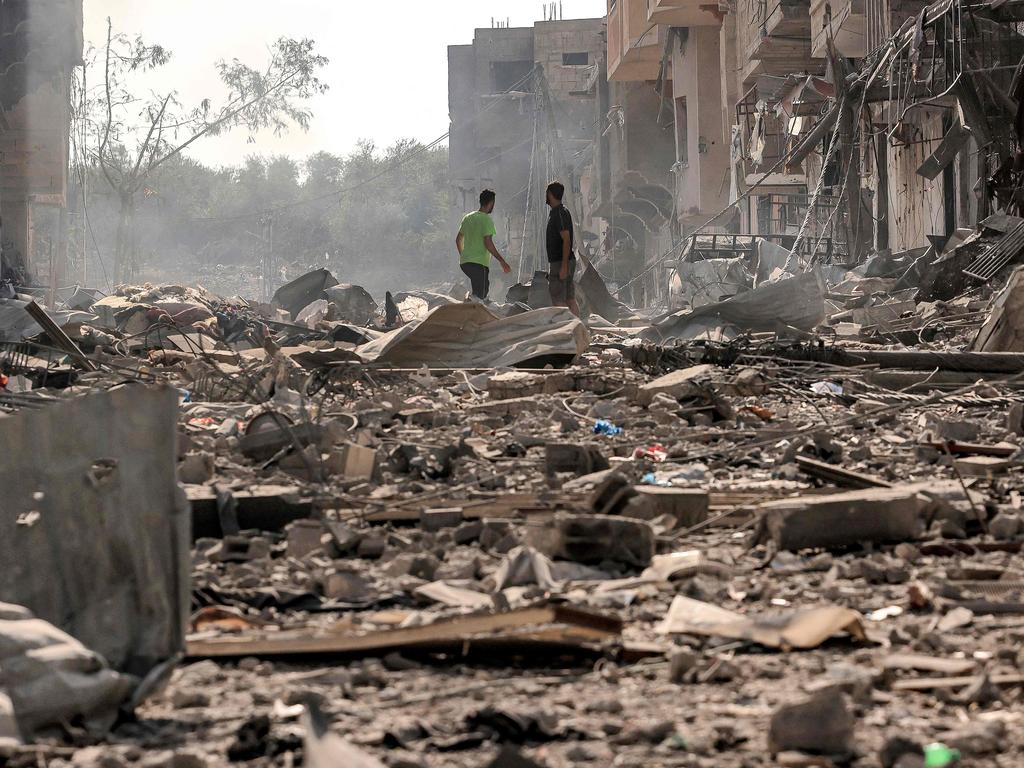 Men stand through debris and destruction littering a street in the Jabalia camp for Palestinian refugees in Gaza City, on the fifth day of battles between Hamas and Israel. Picture: AFP