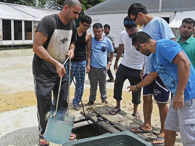 Asylum seekers fill waste bins with water from a makeshift well inside the detention centre. Picture: Brian Cassey