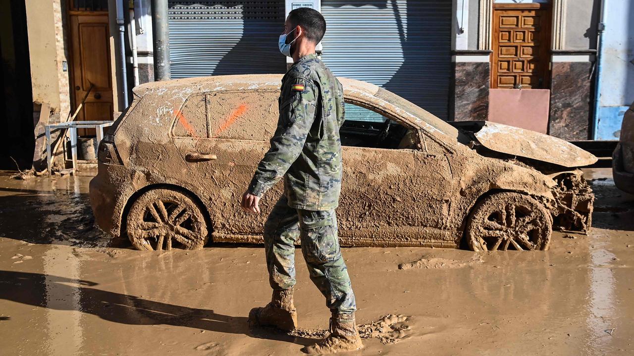 A soldier walks past a flood-destroyed car in Massanassa on November 2. Picture: Jose Jordan/AFP