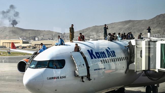 Afghan people climb atop a plane as they wait at the airport in Kabul. Picture: AFP