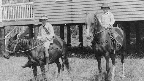 Ready for school on horseback, ca. 1918. Two Bundaberg children with their horses, Trixie and Lassie, prepared for their school day. Source: State Library of Queensland