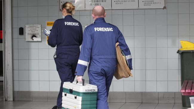 Forensic police officers enter the building.