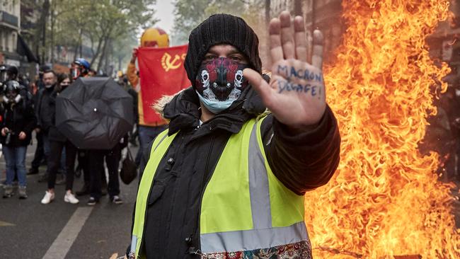 A Gilet Jaune, or yellow vest, protestor stands in front of a burning barricade holding his hand up with an inscription calling for President Macron to resign as May Day Protest turn violent near Place de la Republique on May 1. Picture: Getty Images