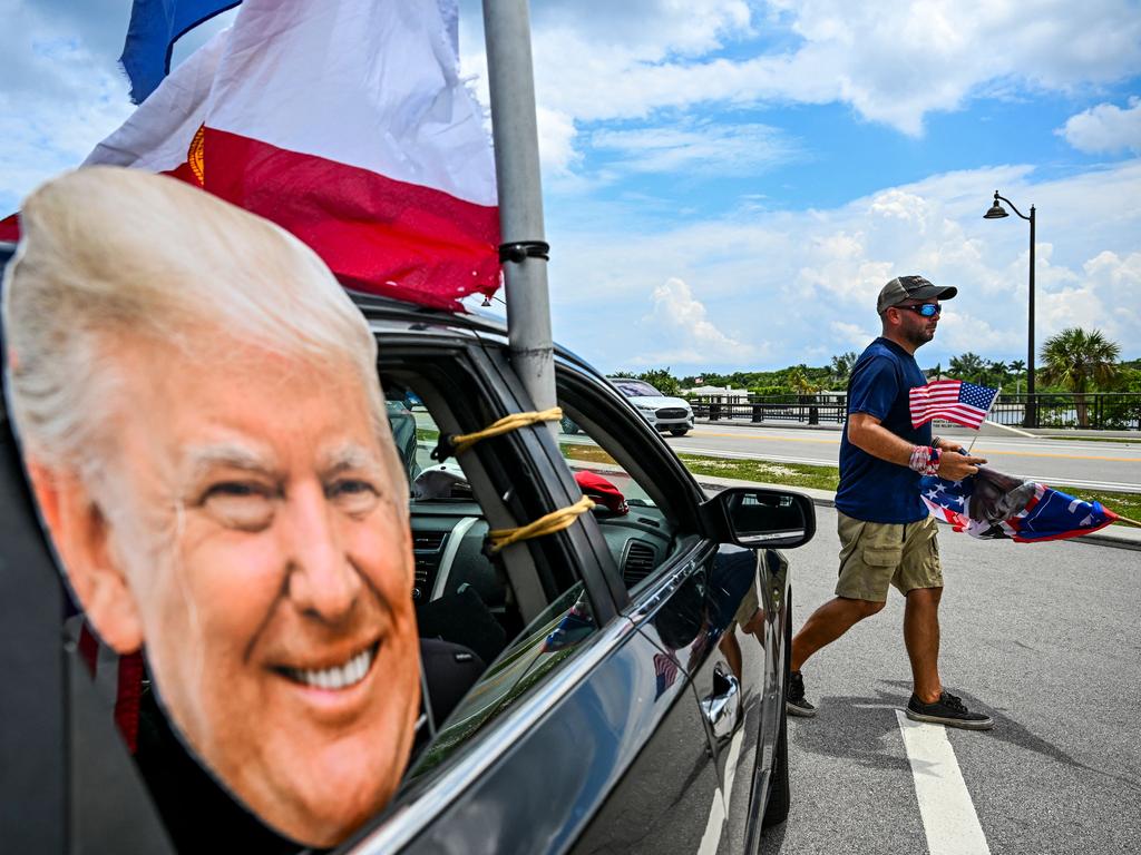 Jestin Nevarez (R), a supporter of former US President Donald Trump, carries an American flag near Trump's Mar-a-Lago residence, in Palm Beach, Florida. Picture: AFP