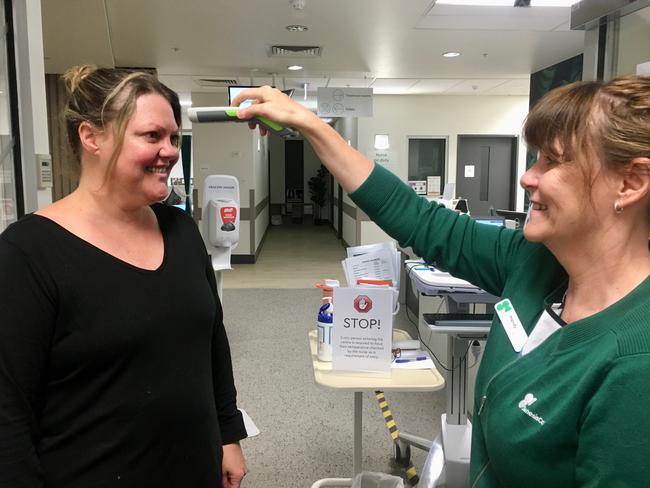 Chelsea mother Emma Harper has her temperature checked before a radiation therapy session at GenesisCare Frankston. Picture: GenesisCare