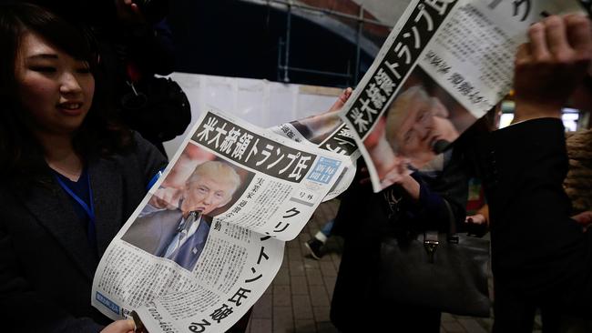 A woman distributes an extra edition of a newspaper in Tokyo featuring the Trump victory. Picture: AP