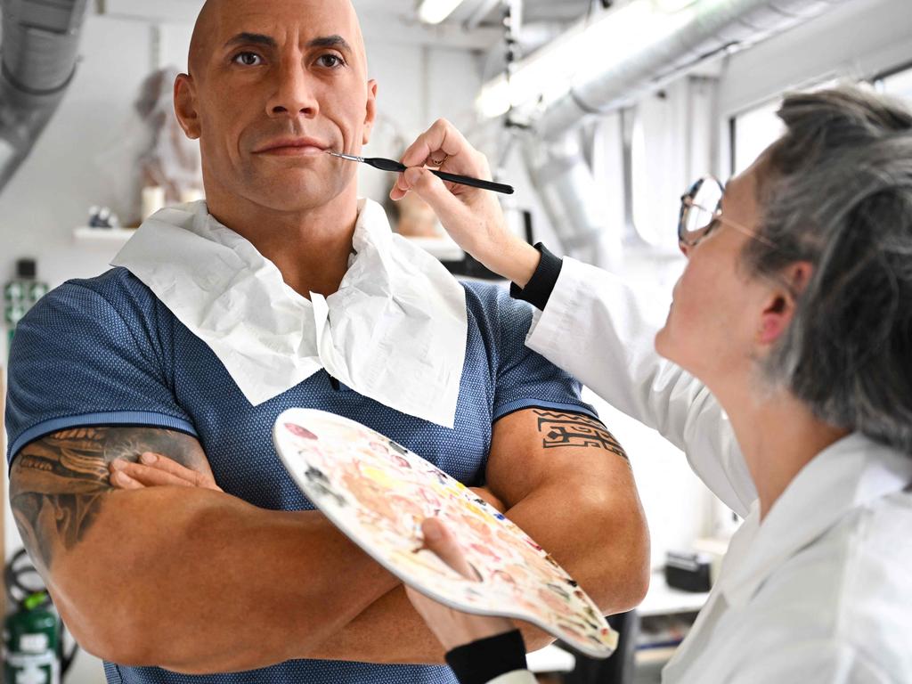 TOPSHOT - An employee adjusts the skin tone on the wax effigy of Dwayne Johnson, after the US actor complained about its pale skin tone, at the Grevin museum in Paris on October 24, 2023. Johnson, who is of Samoan and Black origin, took to Instagram this weekend to joke about the Grevin Museum's botched wax figure, which appeared to depict him with white skin, and bears only a vague likeness to his features. (Photo by Stefano RELLANDINI / AFP)