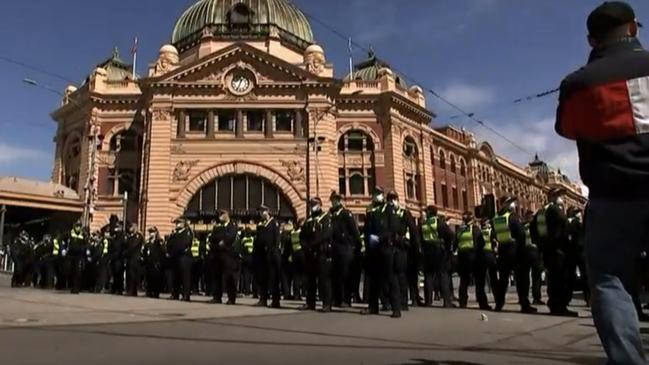 A wall of police set up outside Flinders Street Station.