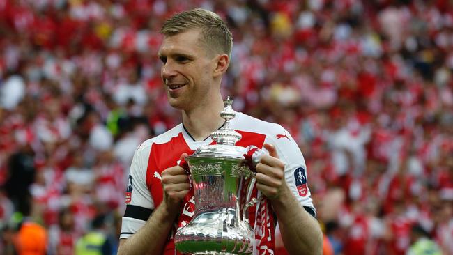 Arsenal's German defender Per Mertesacker holds the trophy as he celebrates on the pitch after their win over Chelsea in the English FA Cup final