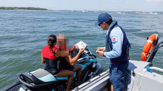 A jet ski rider showing his license and registration to NSW Maritime principal manager Shane Davey after he was stopped for a document check. The driver was doing everything correctly and left to go about his day. Picture: Max Mason-Hubers