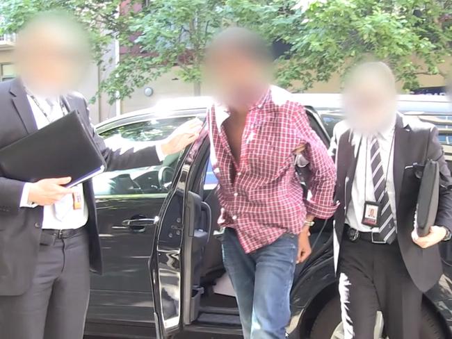 Officers walk the man into a police station. Faces have been blurred by police.