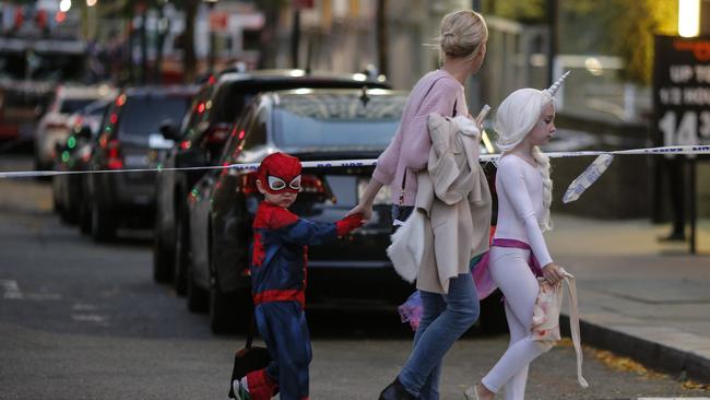 Children in Halloween costumes are led away from the scene by their mother. Picture: AFP