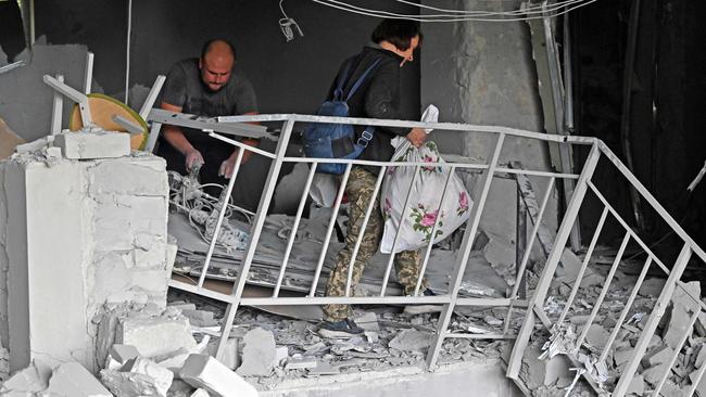 Residents carry out their belongings from a building partially destroyed by a missile strike in Kharkiv. Picture: AFP