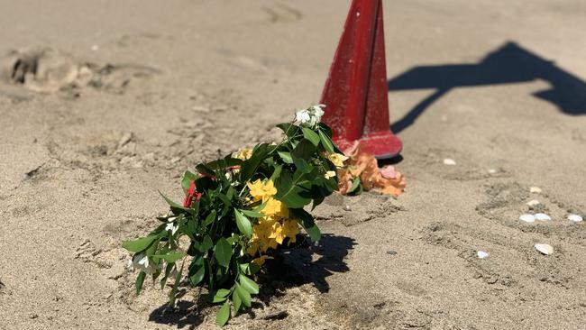 Flowers left at the base of a red flag at Eimeo Beach closed after 14-year-old boy Mark Angelo Ligmayo was stung by a box jellyfish on Saturday, February 26, 2022. He died at Mackay Base Hospital. Picture: Tara Miko