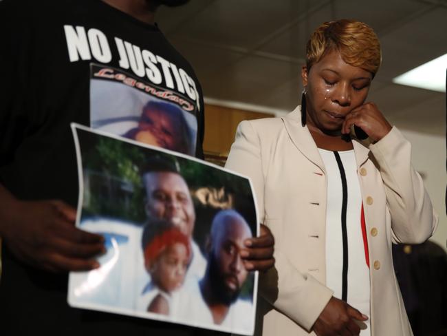Lesley McSpadden, the mother of 18-year-old Michael Brown, wipes away tears as Brown's father, Michael Brown Sr., holds up a family picture of himself, his son, top left, and a young child. AP Photo/Jeff Roberson
