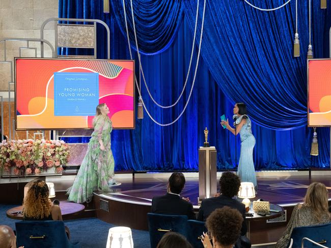 At a social distance, director/writer Emerald Fennell accepts the Oscar for Best Original Screenplay from Regina King. Picture: Getty Images