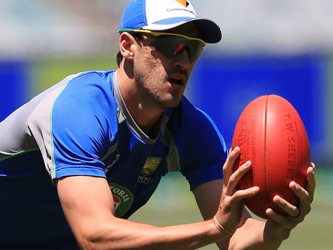 Mitchell Starc with a football at the Australian cricket team’s MCG training session. Picture: Wayne Ludbey