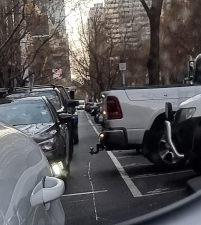 A large American-style ute is overhanging a car space on Lonsdale St.