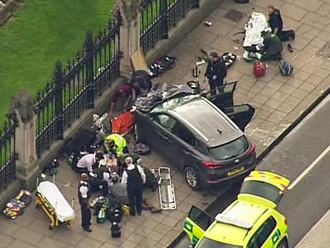 Police officers gather around the crashed Hyundai, adjacent to Parliament House. Picture: ITN via AP