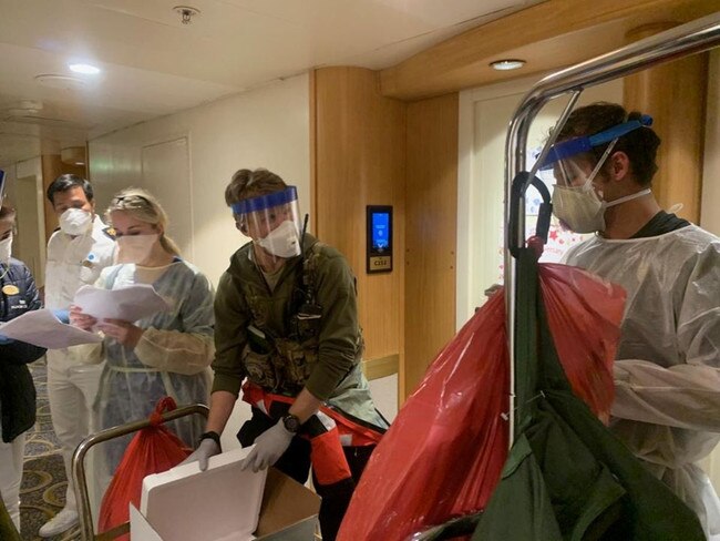 Medical personnel Guardian Angels with the 129th Rescue Wing, alongside individuals from the CDC don full personal protective equipment as they prepare to test passengers.