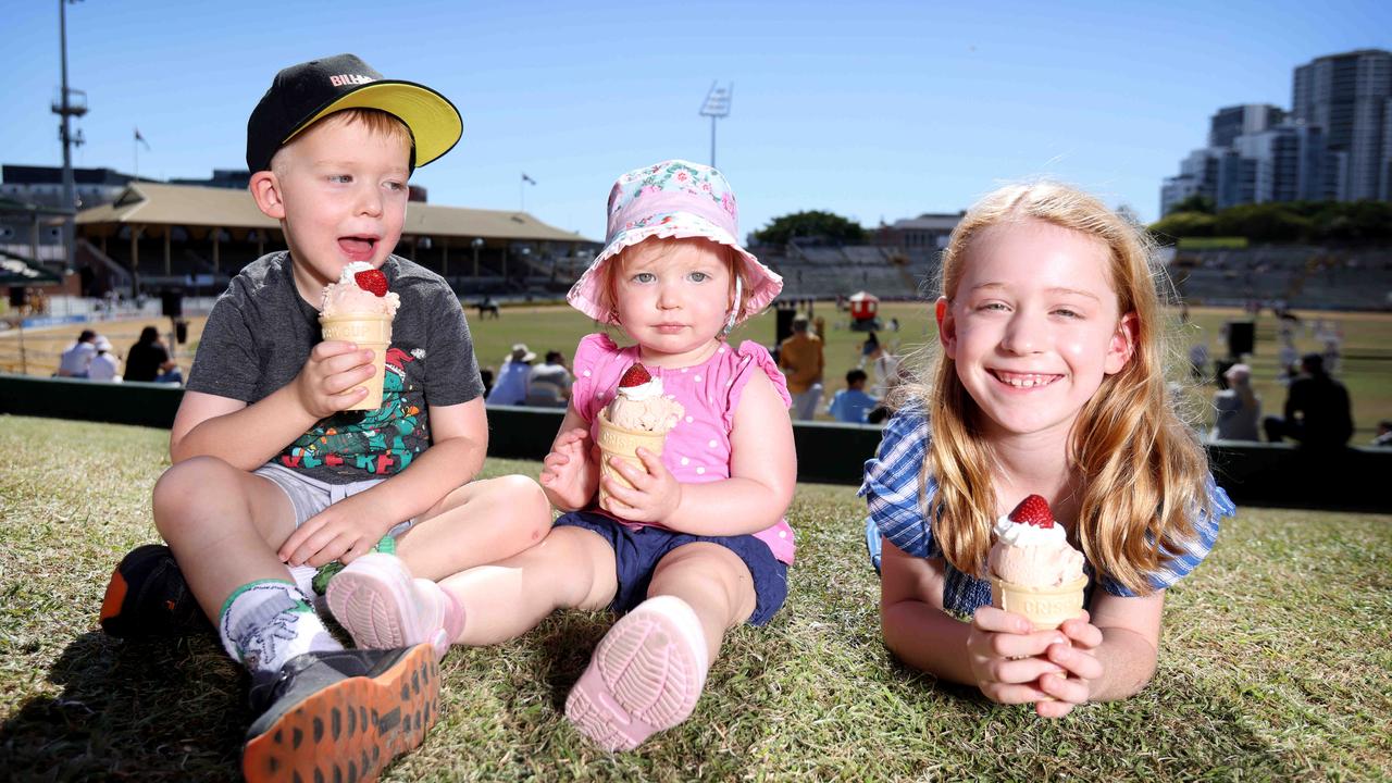 Caleb, 4, Lara 18 months, and Kate Schipper, 7, enjoy strawberry sundaes on the hill on the last day of Ekka. Picture: Steve Pohlner