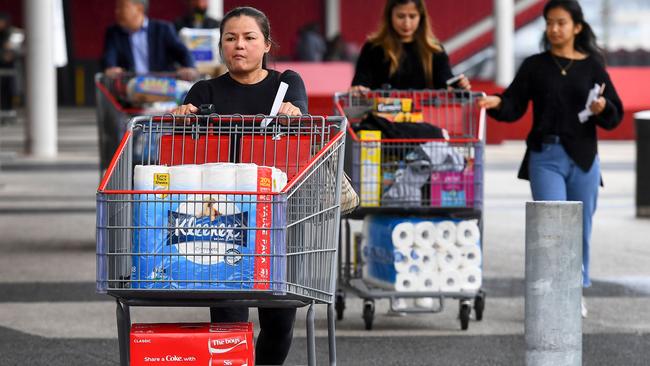 People leave a Costco warehouse with rolls of toilet paper among their groceries in Melbourne on March 5, 2020. Picture: AFP.