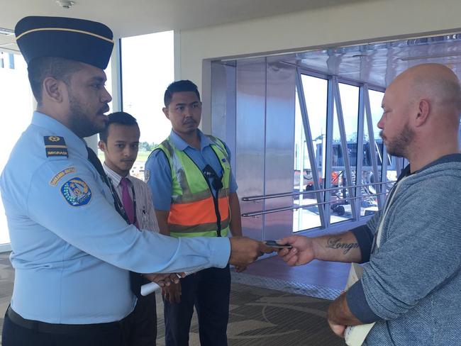 Ricky Longmuir is escorted onto the plane. Picture: Supplied