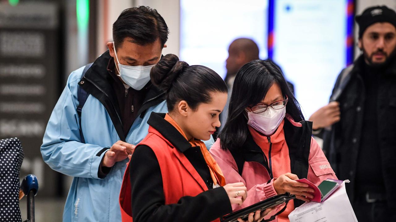 An airport worker (centre) helps out passengers wearing protection masks coming from China, with a medical survey at the arrival Terminal in Charles De Gaule Airport, in Roissy on January 26, 2020. Picture: Alain Jocard / AFP