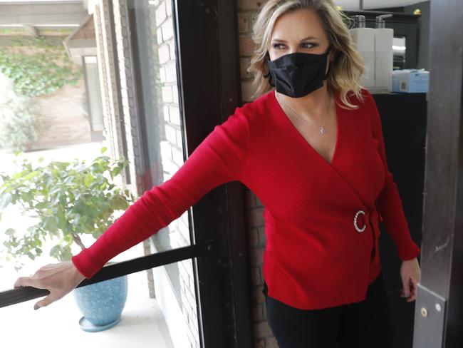 AShelley Luther wears a mask as she opens the door for a visitor to enter her just reopened Salon A la Mode in Dallas. Picture: AP