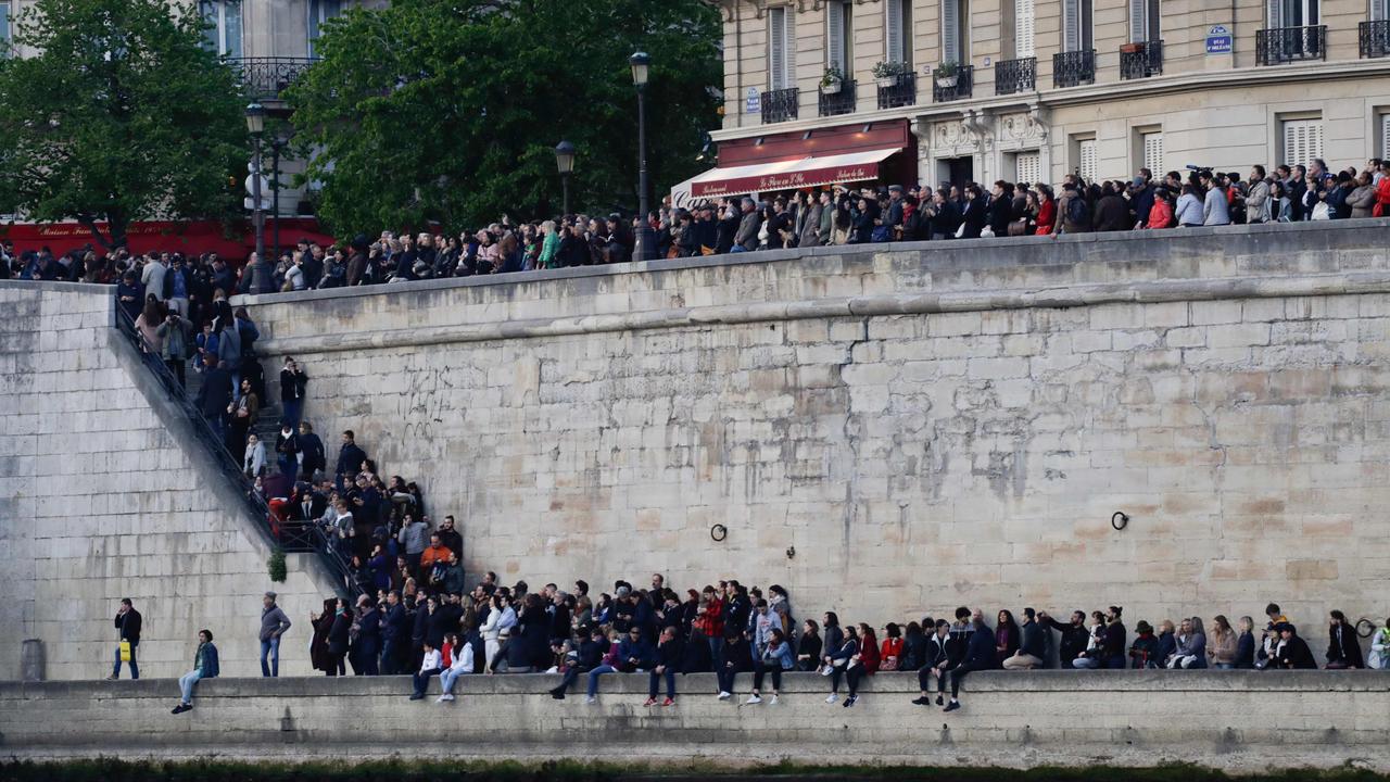 People gathered on the banks of the Seine river, watching the destruction. Picture: Thomas Samson