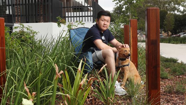 Buyer Freddy Yang sits on the nature strip, where he says the courtyard of his Kogarah unit should be. Picture: Richard Dobson