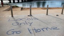 A blunt spray painted "locals only" message in a car park on the edge of Narrabeen Lagoon, at North Narrabeen Beach. Picture: Facebook