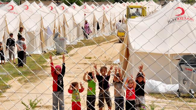Syrian refugee children wave from the Boynuyogun Turkish Red Crescent camp in the Altinozu district of Hatay, Turkey near the Syrian border. Picture: AFP MUSTAFA OZER