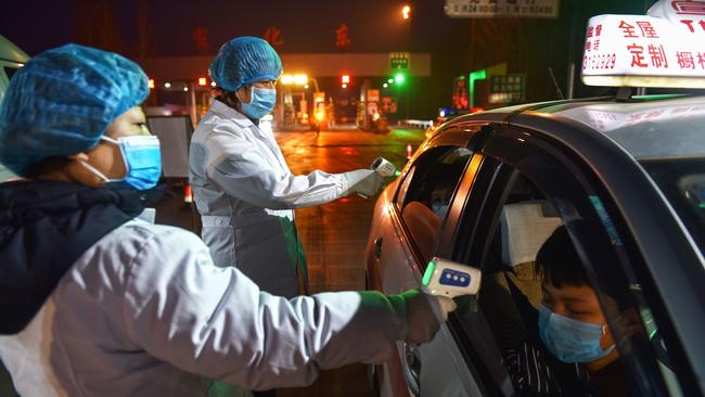 A staff member checking the temperature of a passenger at an exit of a highway in Zhangjiakou in China's northern Hebei province. Picture: AFP