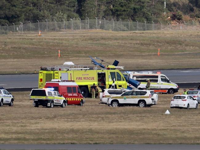 Emergency services surround the crashed helicopter at Hobart Airport. Picture: LUKE BOWDEN