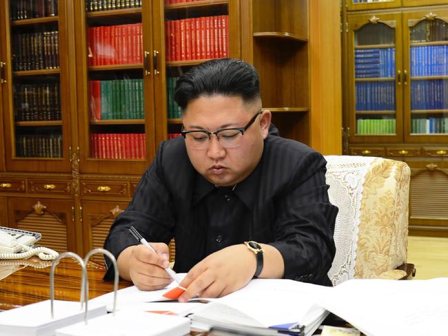 North Korean leader Kim Jong-un signs the order to carry out the test-fire of the intercontinental ballistic missile Hwasong-14. Picture: KNCA/AFP