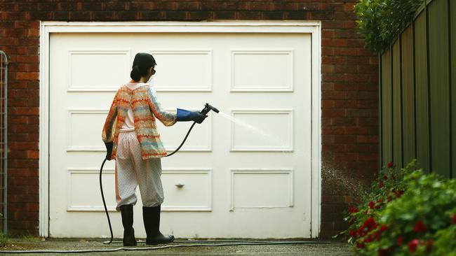 A woman uses a trigger nozzle hose to water her plants. Gardeners will need to use buckets and watering cans from Tuesday. Picture: Sam Ruttyn