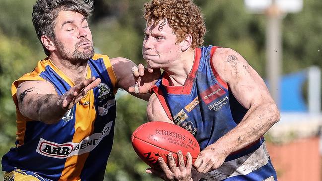 Gisborne's Flynn Lakey dishes off a handball under pressure from Golden Square opponent Hamish Morcom. Picture: SAA Imaging (supplied)