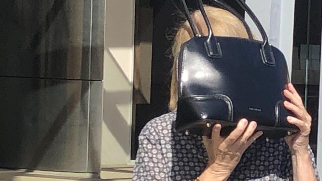 Pamela Anne Jessep hides behind her handbag as she leaves Southport Magistrates Court.