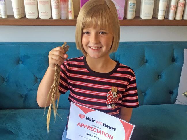 ROCK STAR: Shelby Probst, 8, holding her hair after she had 35cm chopped off for charity Hair with Heart. The children's charity sends donated hair to specialised wig makers to make wigs for children who have suffered hair loss through illness or a medical condition.