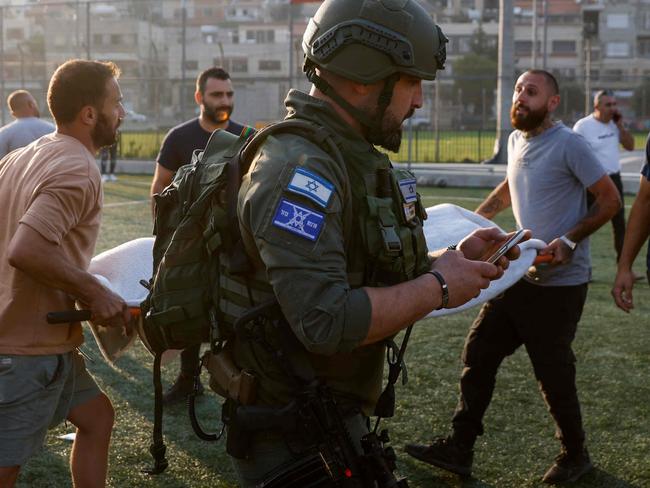 TOPSHOT - Israeli security forces and medics transport casualties from a site where a reported strike from Lebanon fell in Majdal Shams village in the Israeli-annexed Golan area on July 27, 2024. Israel's emergency medical service Magen David Adom said at least nine people were killed and 34 wounded including 17 in critical condition, after a rocket fired from Lebanon had hit the town of Majdal Shams in the Israeli-annexed Golan Heights. (Photo by Jalaa MAREY / AFP)